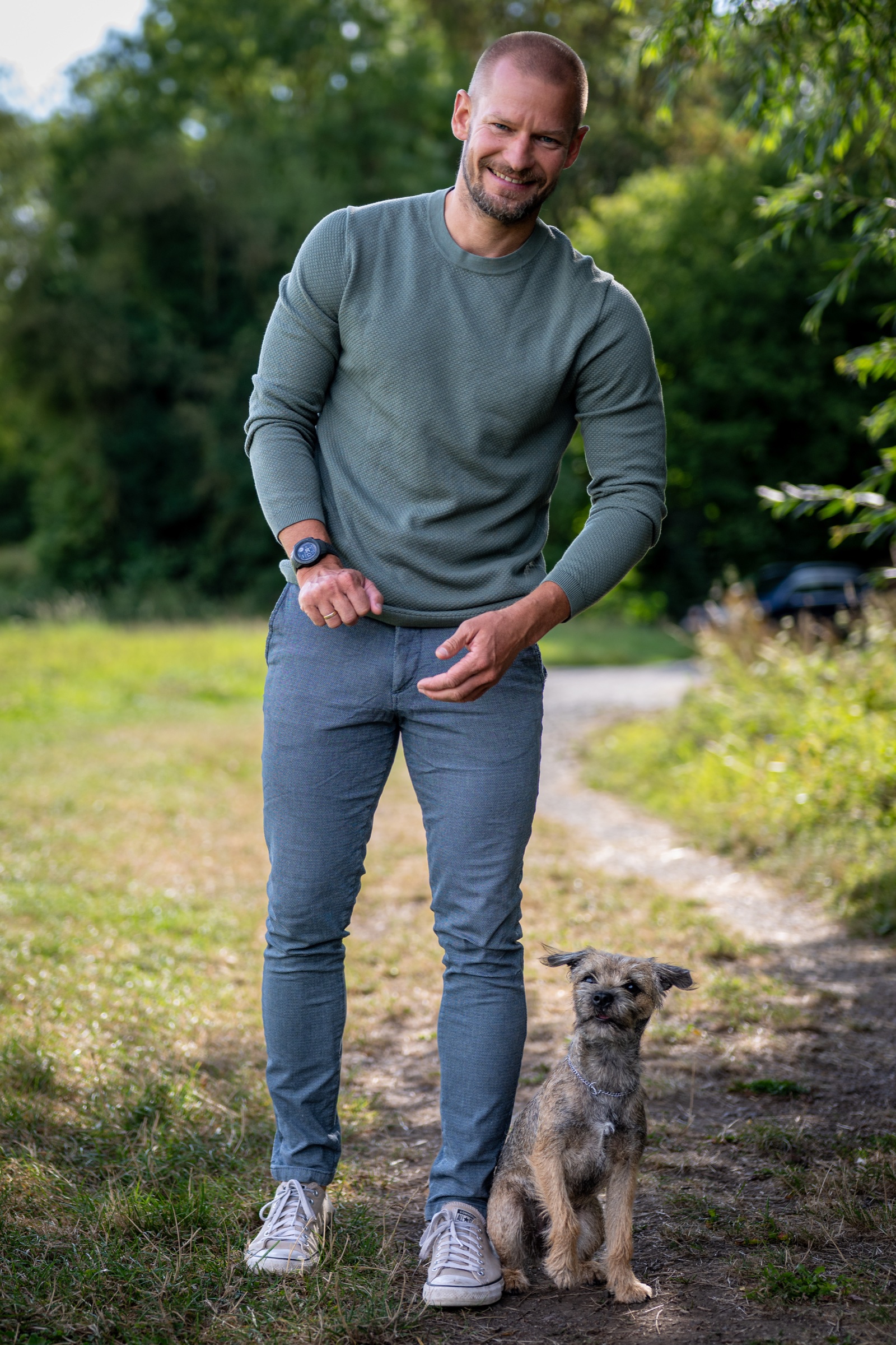 Jan Roland steht gemeinsam mit einem Border Terrier auf einem Waldweg